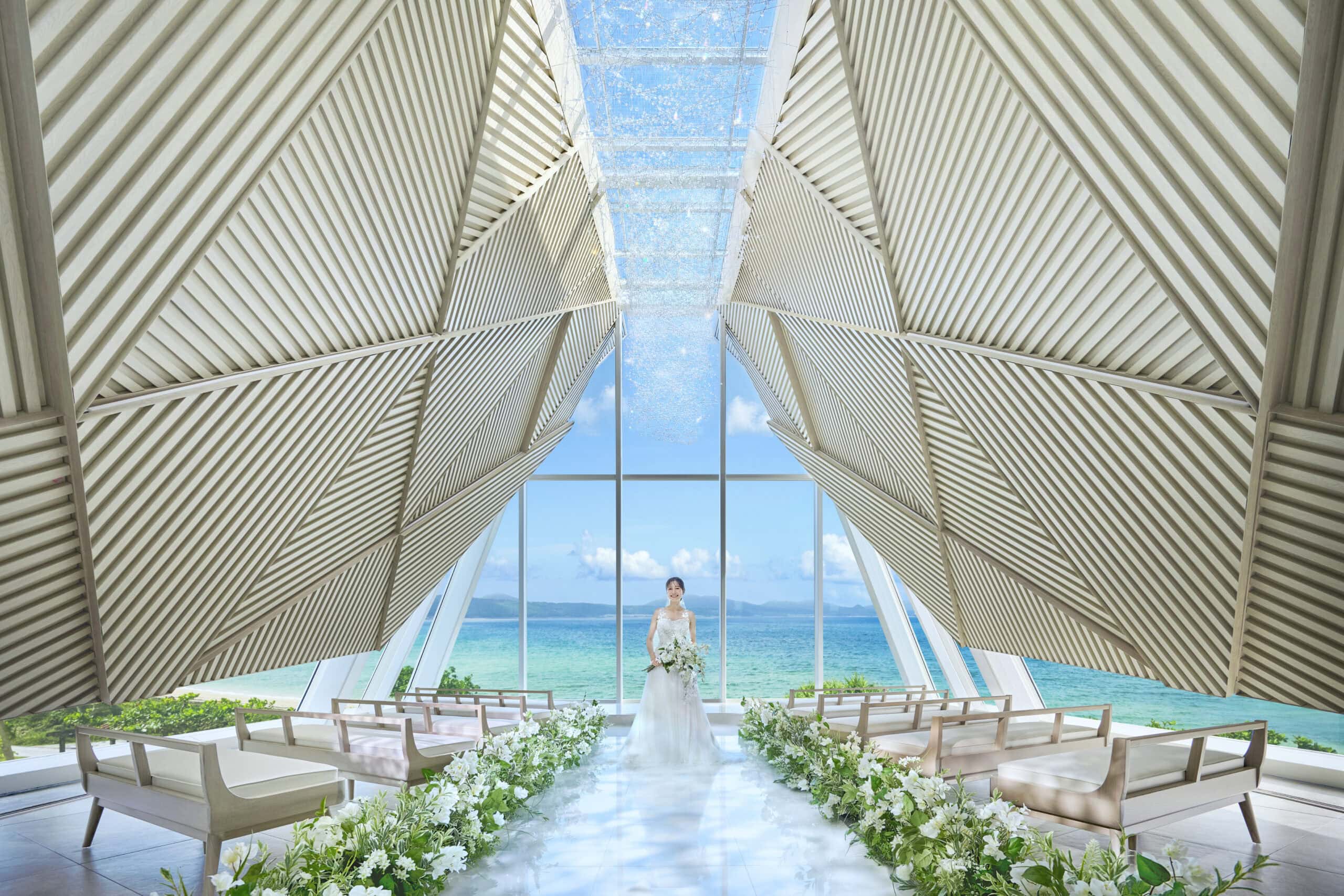 沖縄の海を背景にしたチャペルでの結婚式の新郎新婦.