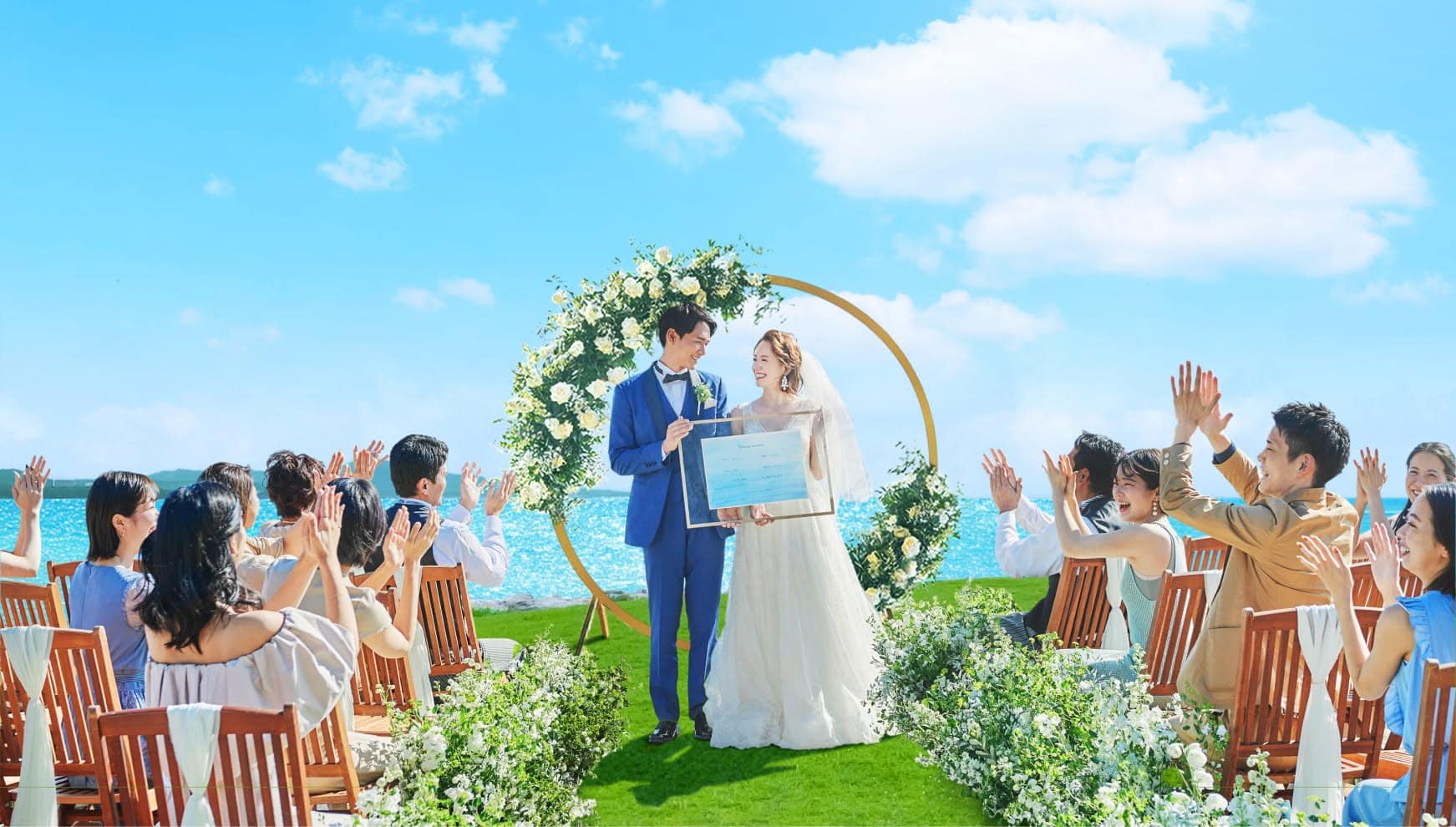 青い海と空の下、幸せな新郎新婦とそれを祝福している参列者たち