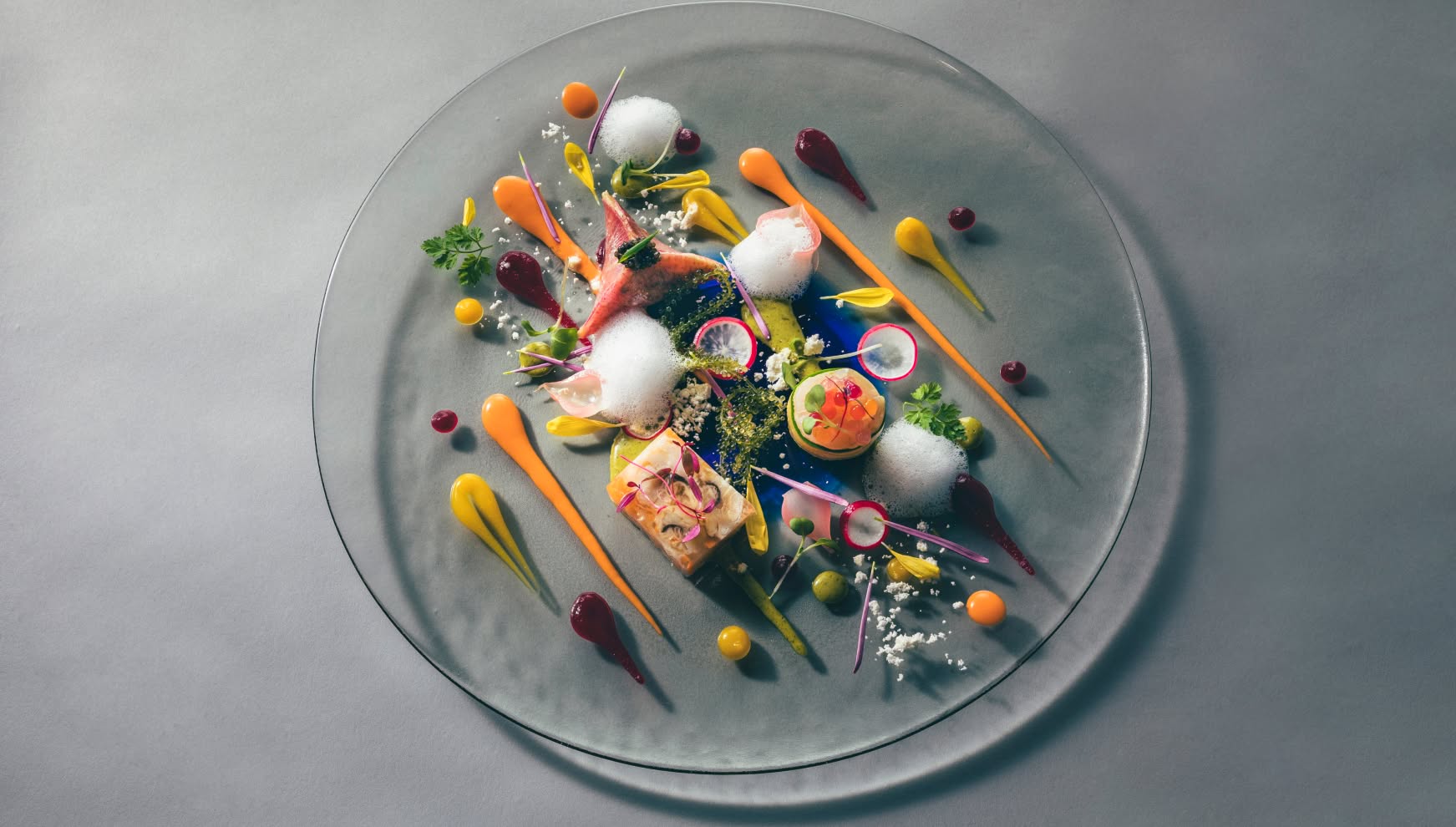 アイネス ヴィラノッツェ 沖縄で提供される、色鮮やかなフレンチのコース料理。透明なガラスプレートに、新鮮な魚介や彩り豊かな野菜、繊細な泡のソースが美しく盛り付けられた、目でも楽しめるウエディングメニュー。
