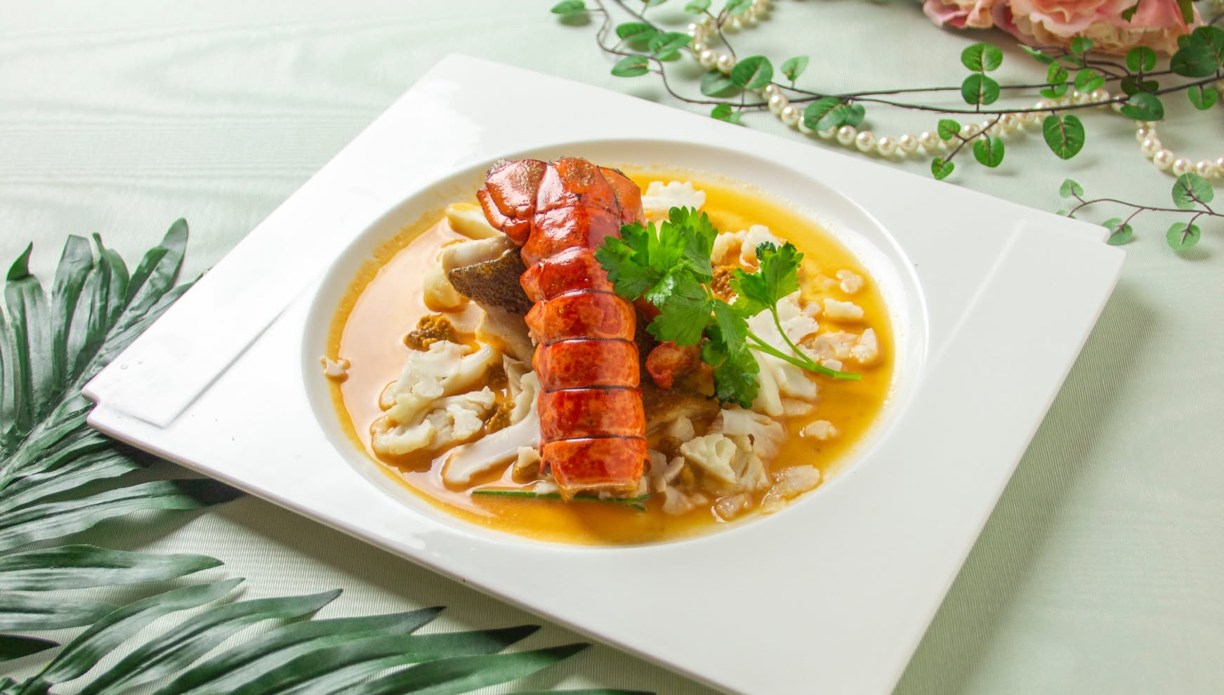 白いスクエアプレートに豪華に盛り付けられた、オマール海老と白身魚のポワレ。濃厚なアメリケーヌソースが敷かれ、カリフラワーなどの温野菜が添えられた、ウエディングの祝宴にふさわしい華やかなメインディッシュ。