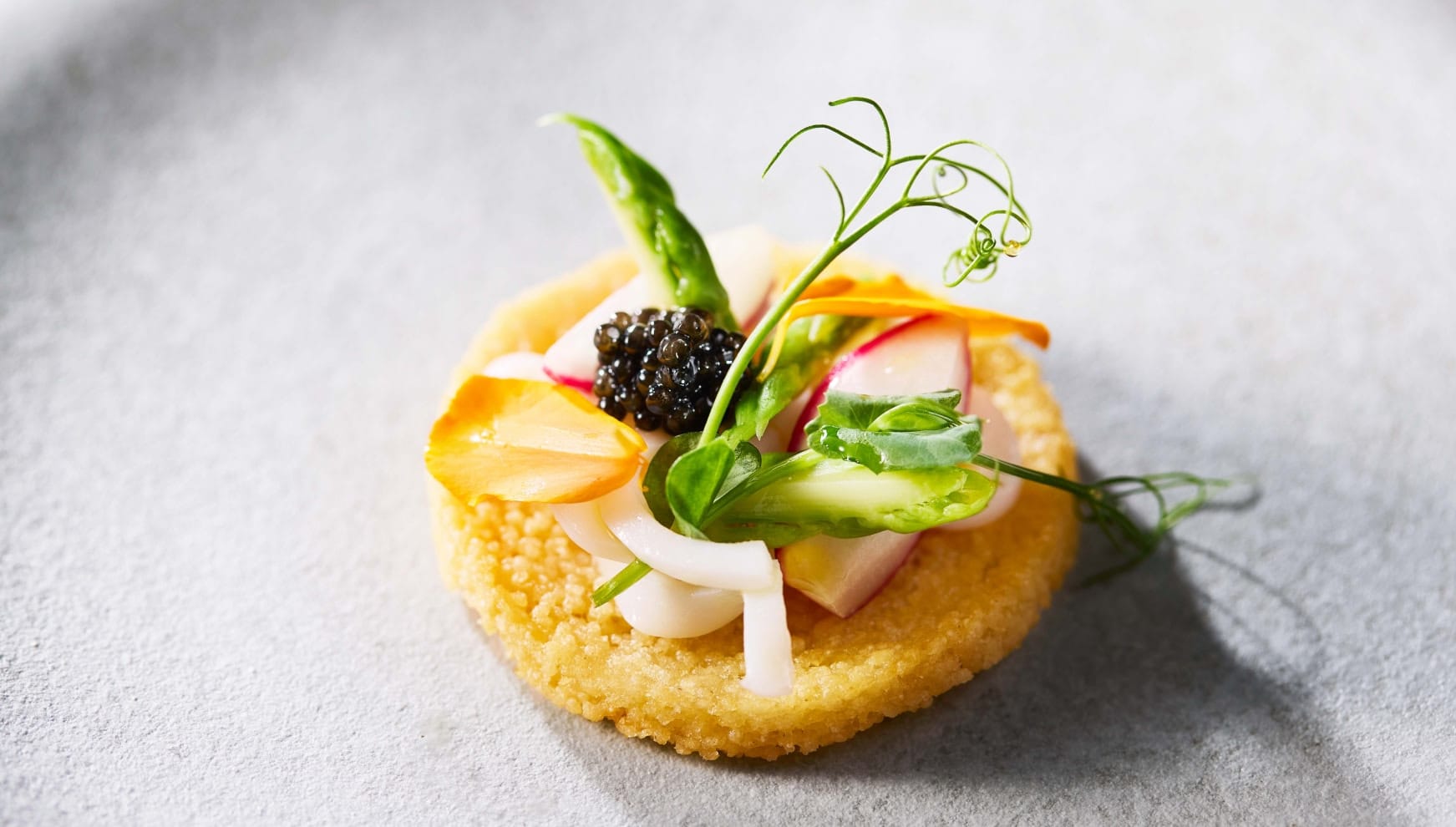 ザ・サーフビーチサイドテラスの婚礼料理。サクサクとした生地の上に、新鮮なイカ、アスパラガス、ラディッシュを盛り付け、贅沢にキャビアを添えた前菜。素材の色鮮やかさと繊細な盛り付けが際立つ、ゲストを魅了する美食の一皿。