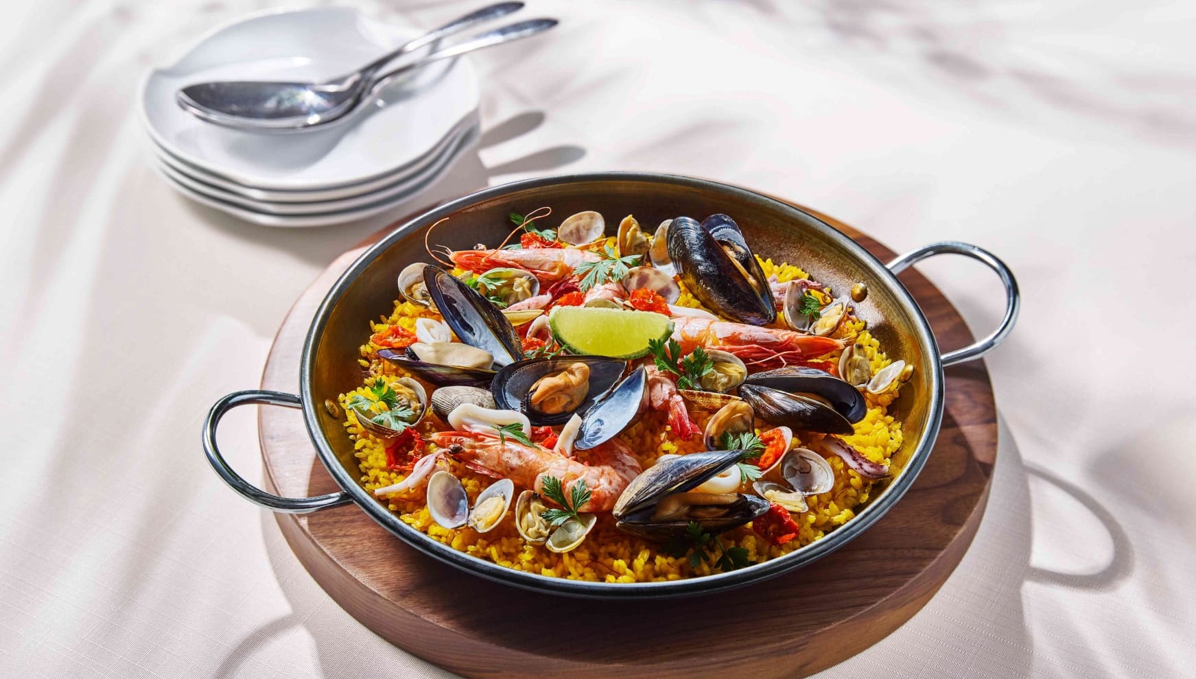 ザ・サーフビーチサイドテラスの婚礼料理として提供される、本格的なシーフードパエリア。大ぶりのエビ、ムール貝、アサリ、イカなどの新鮮な魚介類が贅沢に並び、レモンとハーブが添えられた彩り豊かな一皿。大人数でシェアするリゾートウエディングらしい華やかなパーティメニュー。