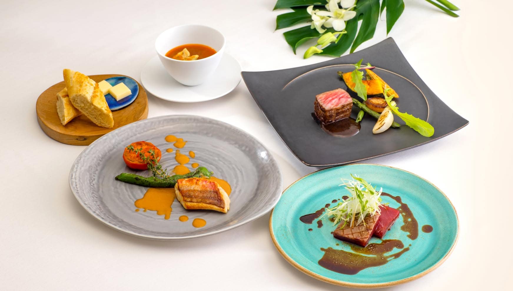 ザ・サーフ シーサイドシーン宮古島で提供される、宮古島の豊かな自然を凝縮した婚礼料理のフルコース。鮮やかなターコイズブルーの皿に並ぶ前菜や、絶妙な焼き加減の牛フィレ肉、香ばしく焼き上げた地魚など、地産地消にこだわった美食の数々。