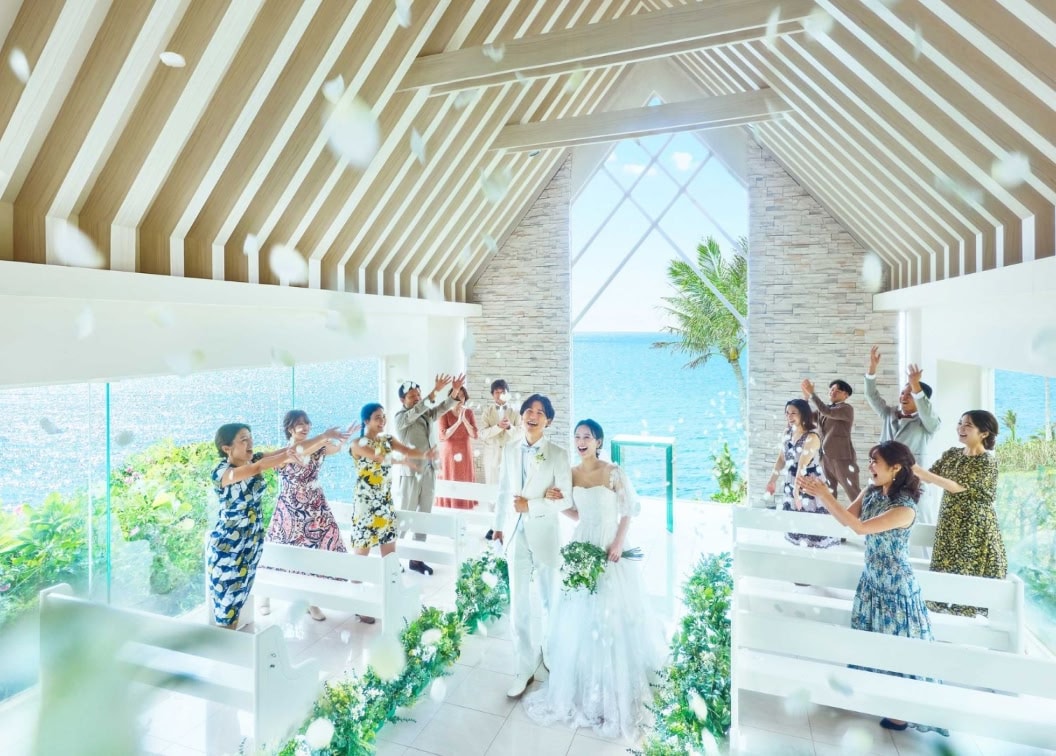 挙式会場で、退場する新郎新婦に参列者が笑顔でフラワーシャワーを浴びせている