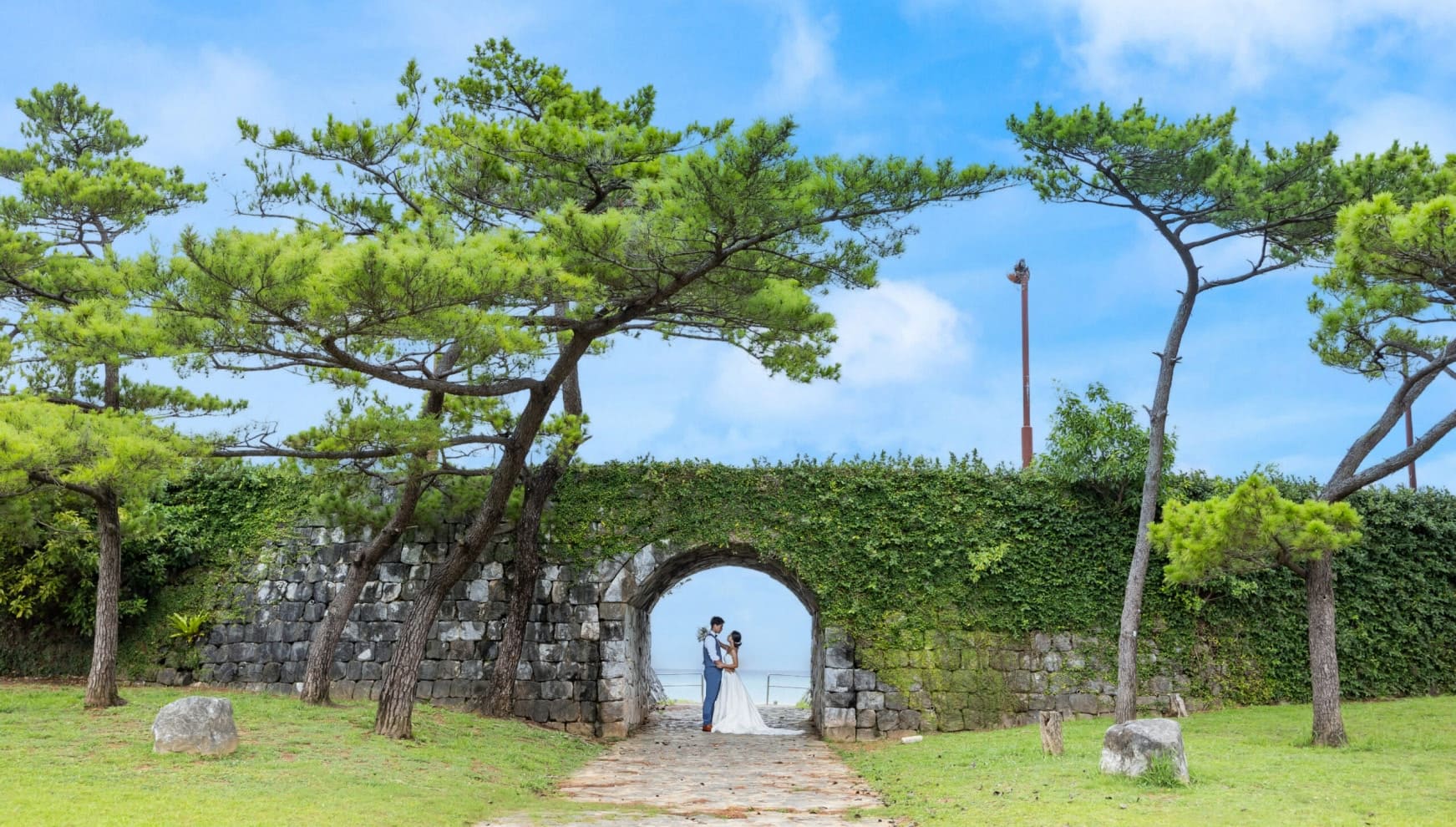 沖縄のグスク（城）を模した石造りのアーチの下で、互いに見つめ合う新郎新婦