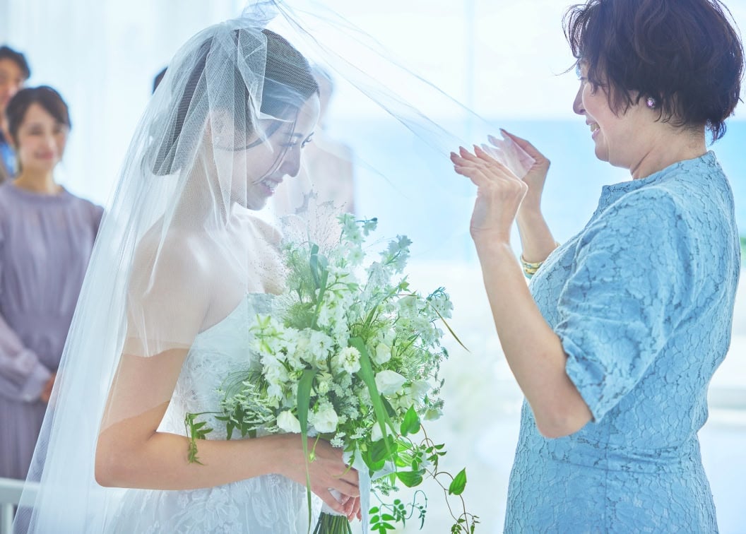 結婚式でのベールダウン。母親が花嫁のベールをゆっくりと下ろしている