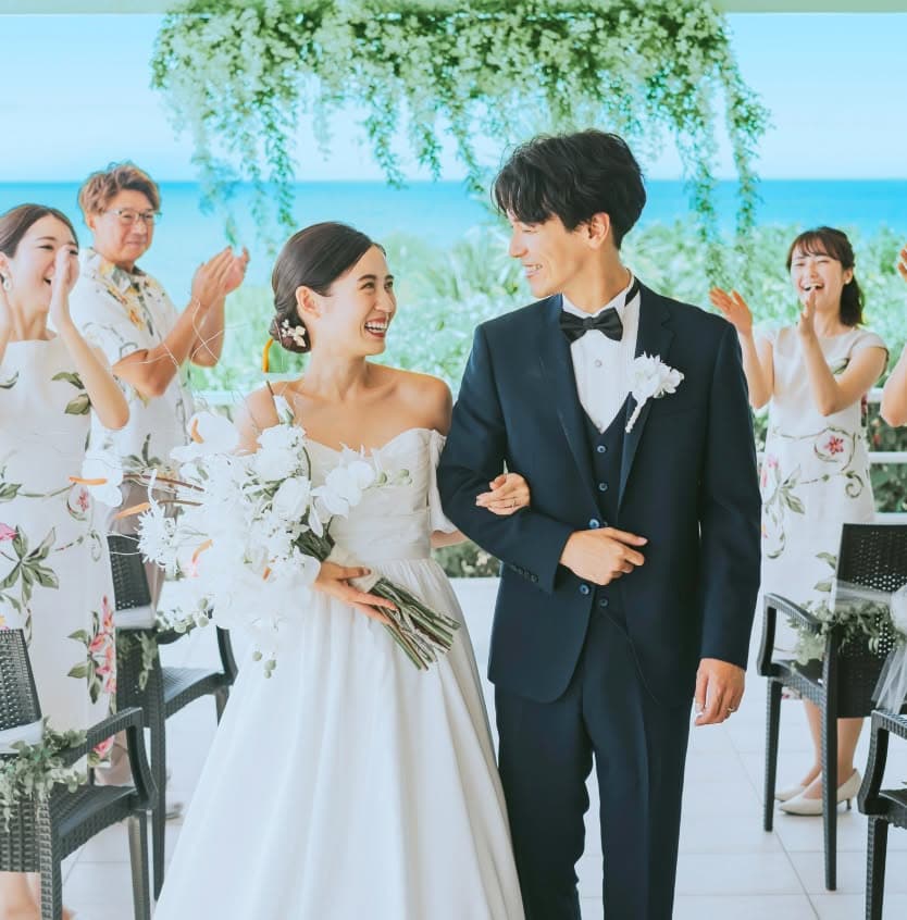 笑顔の新郎新婦と、お揃いや色とりどりのかりゆしウェアを着て祝福する参列者たち