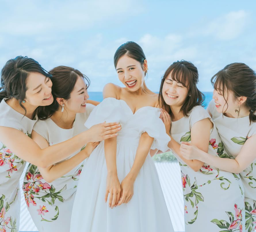 花嫁を中心に、両隣にかりゆしウェアを着た友人たちが並んで、全員で笑顔を見せている集合写真