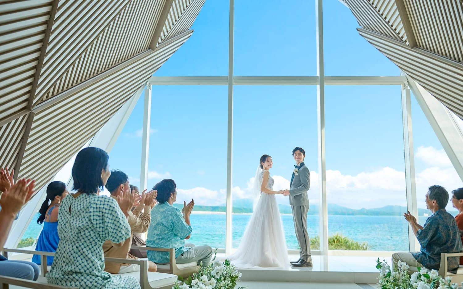沖縄の絶景を背景にしたウエディングセレモニーの新郎新婦.