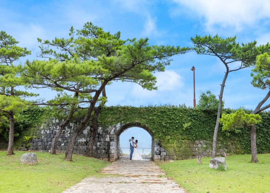 沖縄のグスク（城）を模した石造りのアーチの下で、互いに見つめ合う新郎新婦