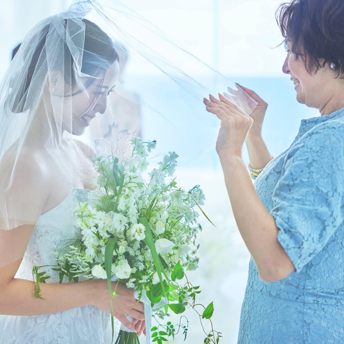 結婚式でのベールダウン。母親が花嫁のベールをゆっくりと下ろしている