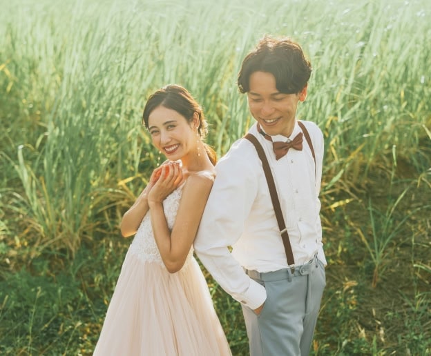 豊かな緑の草木を背景に、幸せそうな笑顔で寄り添う新郎新婦